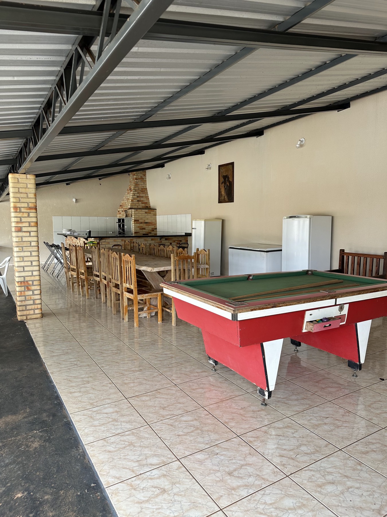 Salão coberto com mesa de sinuca e mesas de madeira