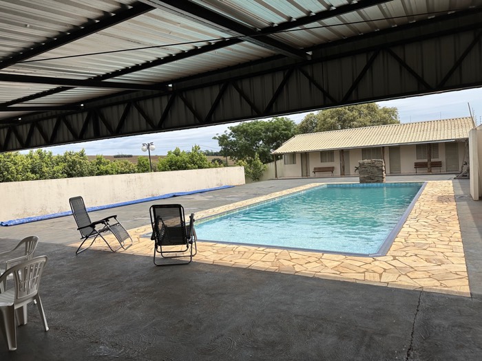 Piscina vista da área coberta, com cadeiras de descanso